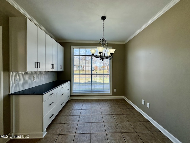 kitchen featuring dark tile patterned flooring, white cabinetry, a notable chandelier, and crown molding