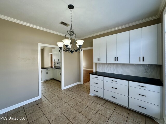 kitchen featuring pendant lighting, white cabinetry, ornamental molding, and a chandelier