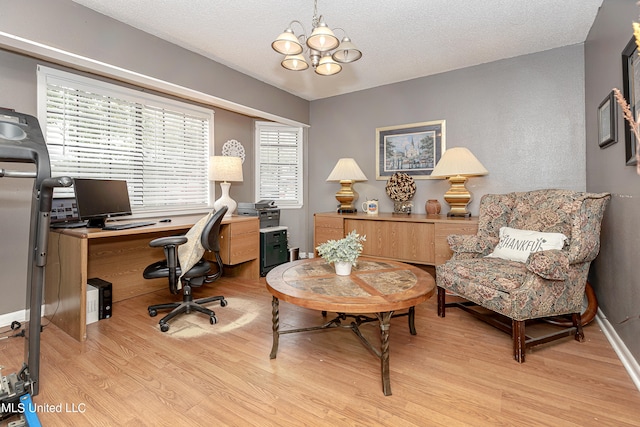 home office with a textured ceiling, light hardwood / wood-style flooring, and a chandelier