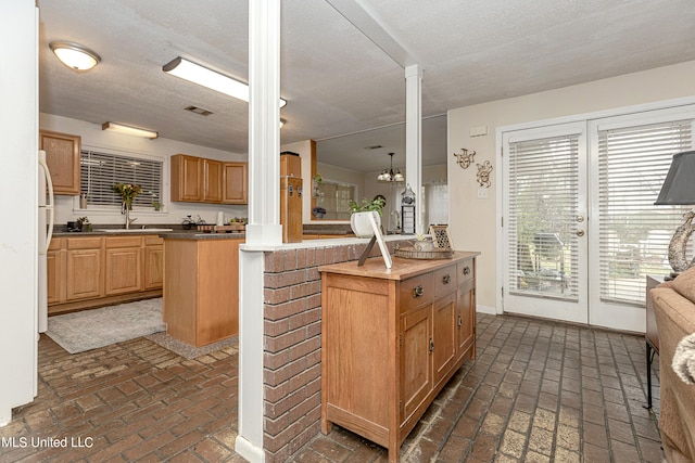 kitchen featuring ornate columns, a textured ceiling, a center island, and kitchen peninsula