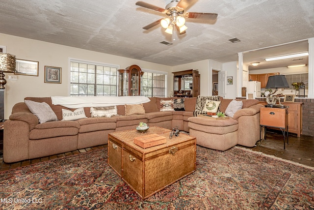 living room with dark hardwood / wood-style flooring, a textured ceiling, and ceiling fan