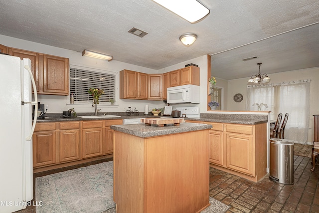 kitchen with white appliances, sink, a center island, hanging light fixtures, and an inviting chandelier