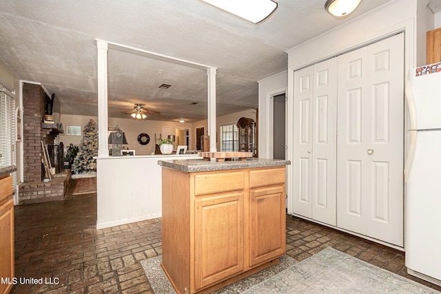 kitchen featuring a kitchen island, a textured ceiling, ceiling fan, white refrigerator, and light brown cabinets