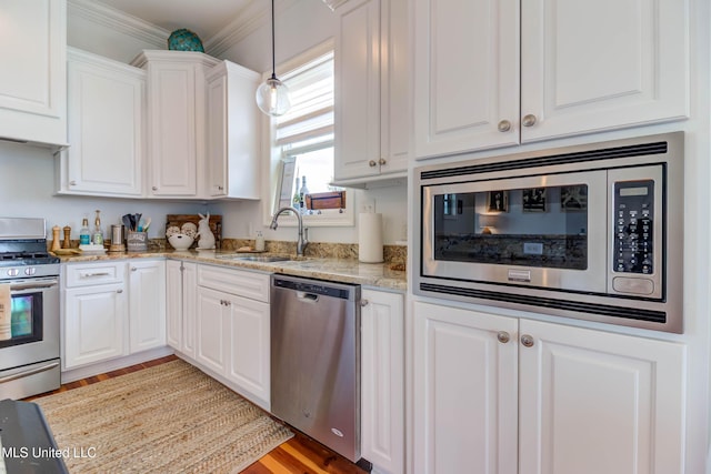 kitchen with appliances with stainless steel finishes, ornamental molding, light stone countertops, white cabinetry, and a sink