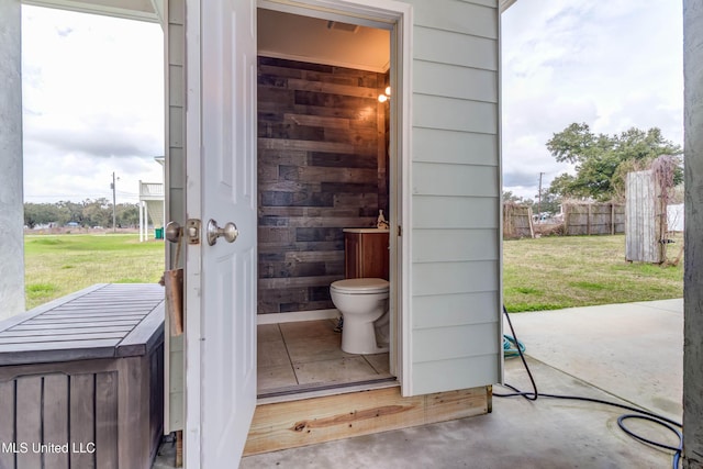 bathroom featuring toilet, wood walls, and concrete floors