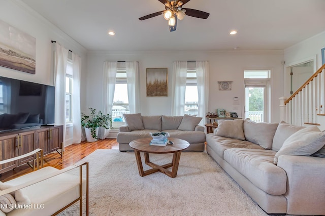 living area featuring light wood-type flooring, a wealth of natural light, and crown molding