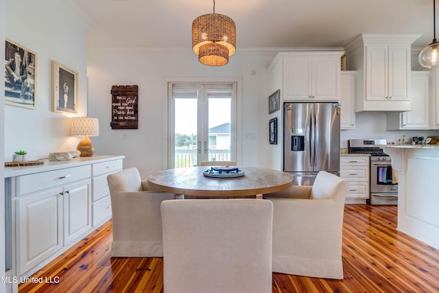 dining room featuring an inviting chandelier, light wood-style flooring, crown molding, and french doors