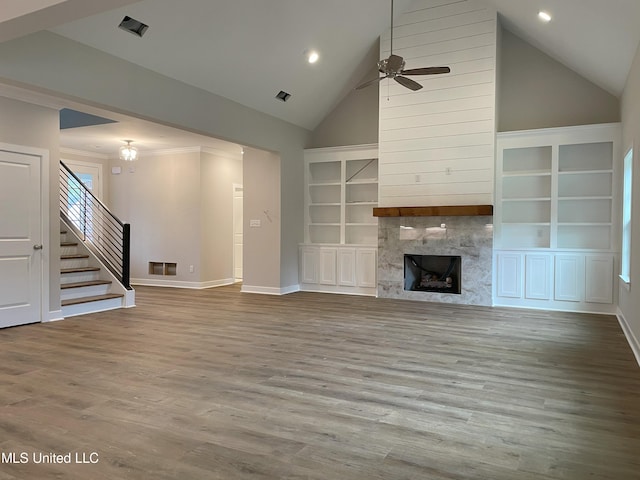 unfurnished living room with a premium fireplace, light hardwood / wood-style floors, high vaulted ceiling, and ceiling fan