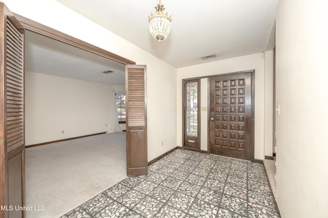 entrance foyer featuring a chandelier, carpet, a textured ceiling, and a healthy amount of sunlight