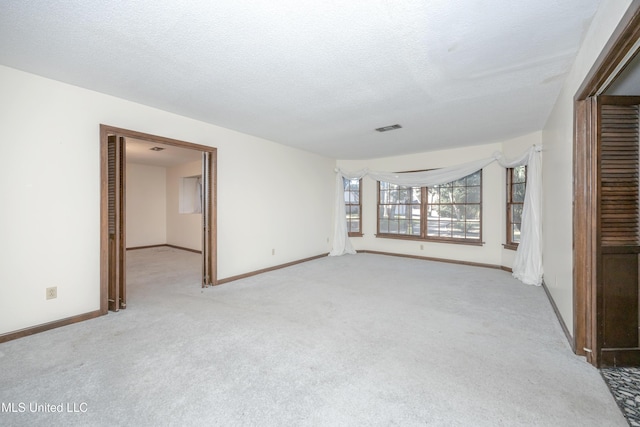 empty room with light colored carpet and a textured ceiling