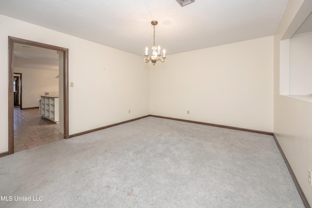 carpeted spare room with an inviting chandelier