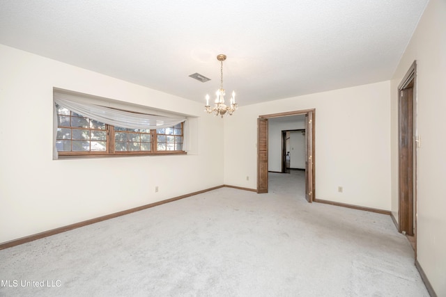 unfurnished room featuring a chandelier, light carpet, and a textured ceiling