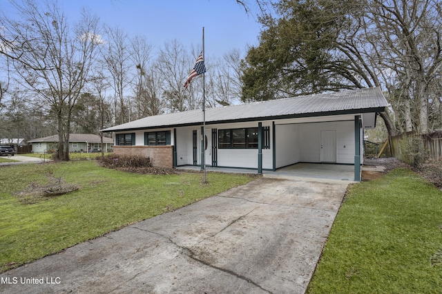 view of front of property with metal roof, concrete driveway, a carport, and a front yard