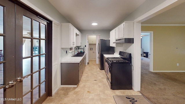 6400 Hans Rd, Moss Point, MS 39562 - kitchen featuring black range with gas stovetop, under cabinet range hood, freestanding refrigerator, light countertops, and white cabinetry