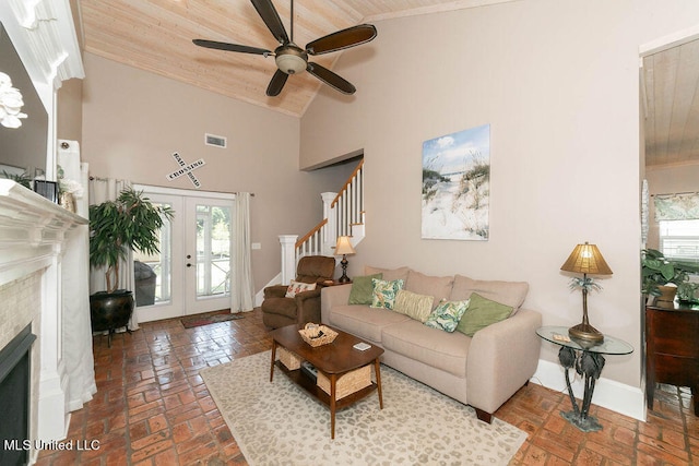 living room featuring a wealth of natural light, a tiled fireplace, high vaulted ceiling, and ceiling fan