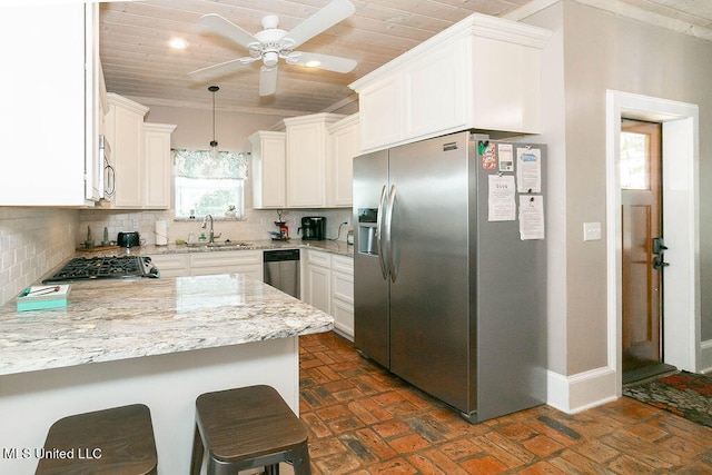 kitchen featuring tasteful backsplash, appliances with stainless steel finishes, sink, kitchen peninsula, and white cabinets