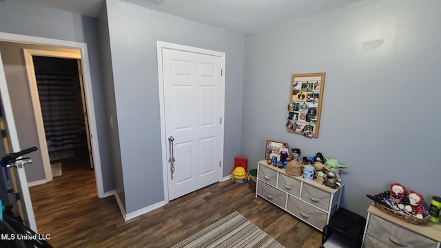 bedroom with dark wood-type flooring and baseboards