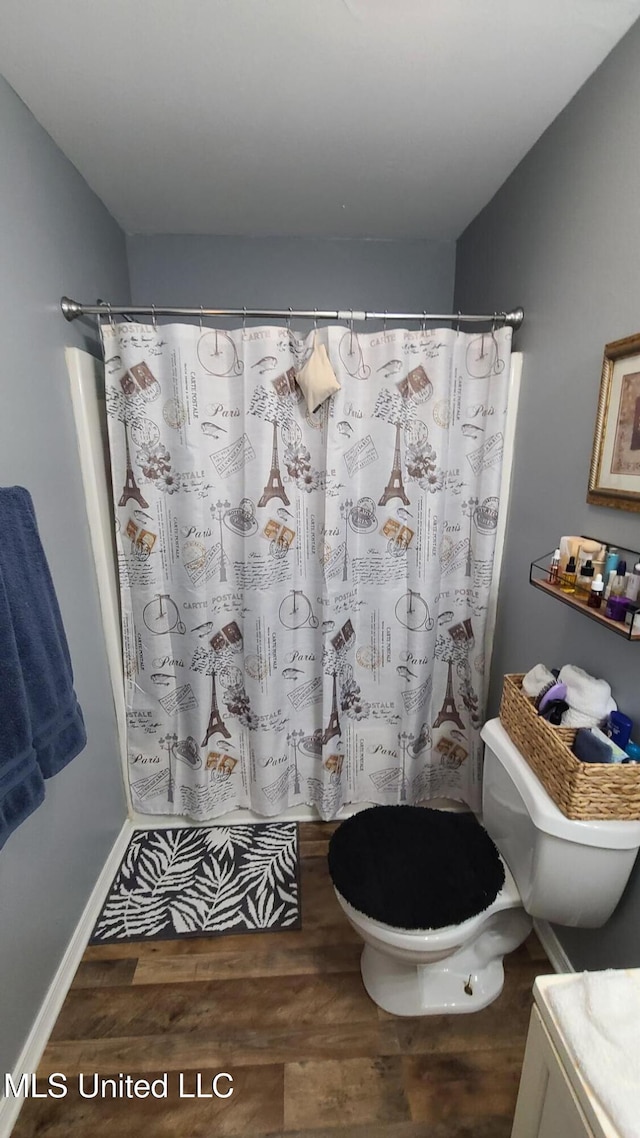 bathroom with curtained shower, baseboards, toilet, and wood finished floors