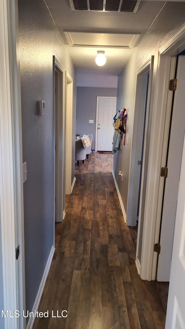 hall featuring attic access, baseboards, and dark wood-style flooring