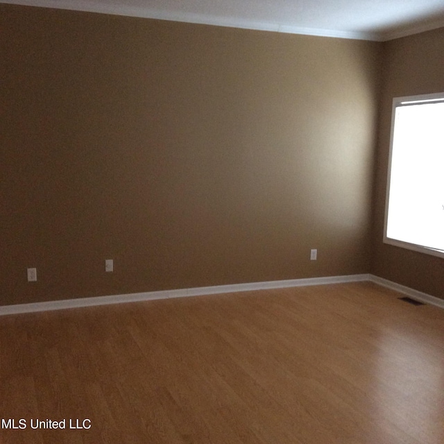 spare room featuring crown molding and hardwood / wood-style flooring