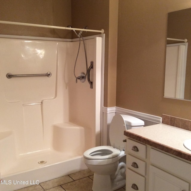 bathroom with vanity, a shower, toilet, and tile patterned floors