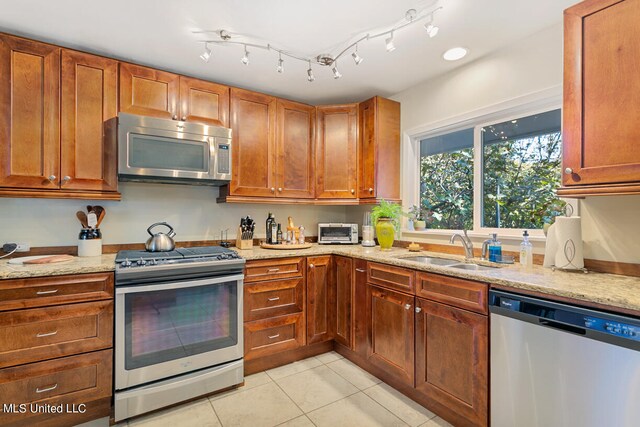 kitchen with appliances with stainless steel finishes, light stone countertops, sink, and light tile patterned floors