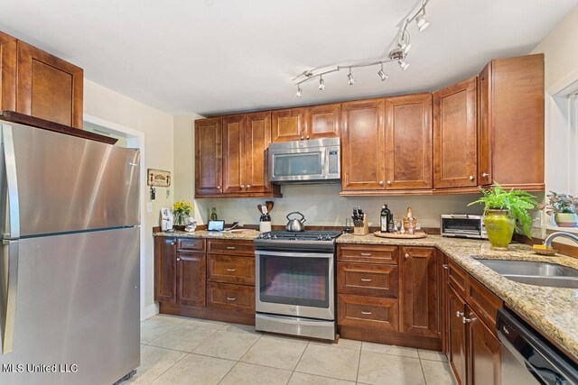 kitchen with sink, light tile patterned flooring, light stone counters, and stainless steel appliances