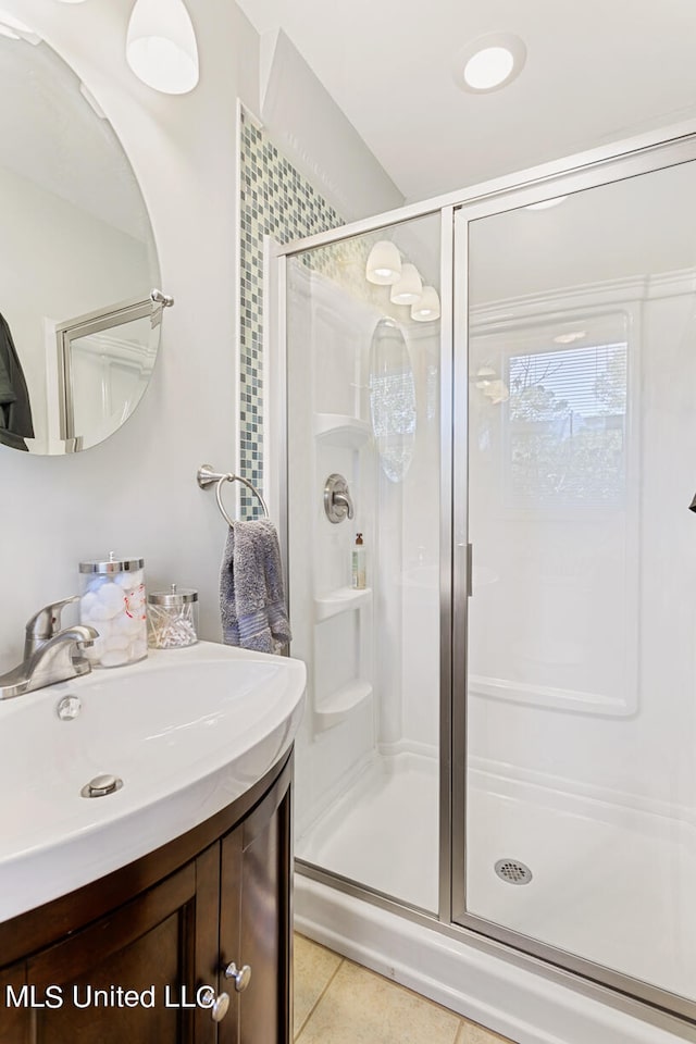 bathroom with a shower with door, vanity, and tile patterned floors