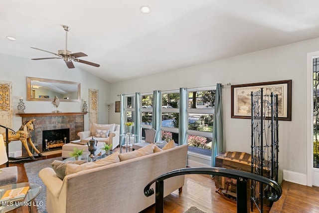 living room with hardwood / wood-style floors, ceiling fan, a tile fireplace, and vaulted ceiling