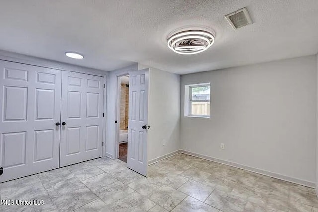 unfurnished bedroom featuring visible vents, a textured ceiling, and baseboards