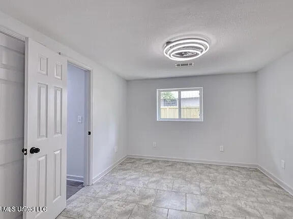 spare room with visible vents, a textured ceiling, and baseboards