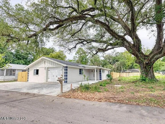 ranch-style home featuring a garage, concrete driveway, and fence