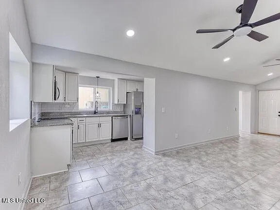 kitchen with backsplash, appliances with stainless steel finishes, open floor plan, white cabinetry, and ceiling fan