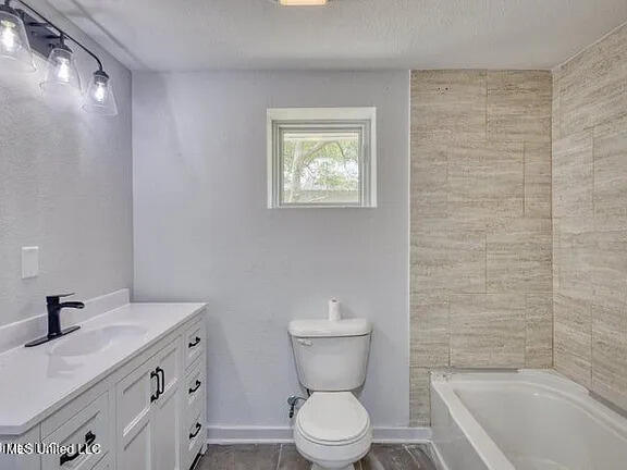 bathroom with toilet, baseboards, and vanity