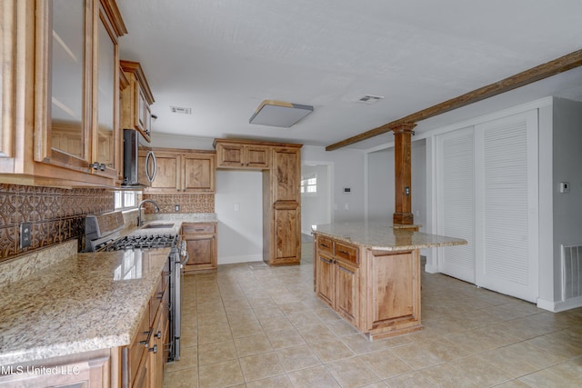 kitchen with stainless steel appliances, light stone counters, decorative backsplash, a center island, and light tile patterned floors