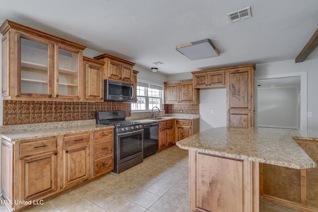 kitchen featuring appliances with stainless steel finishes, light stone countertops, decorative backsplash, light tile patterned floors, and sink