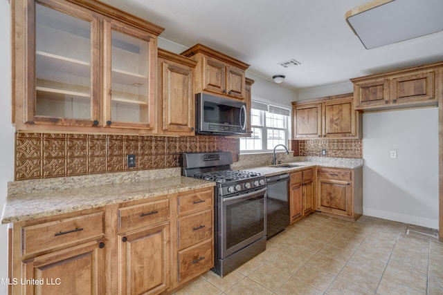 kitchen featuring tasteful backsplash, stainless steel appliances, light stone counters, light tile patterned floors, and sink