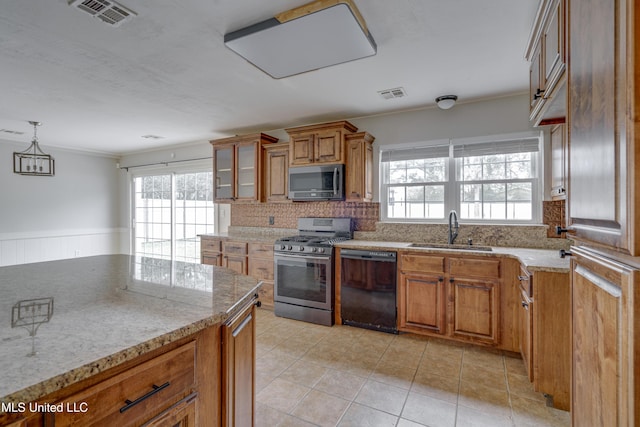 kitchen with sink, light stone counters, appliances with stainless steel finishes, light tile patterned flooring, and pendant lighting