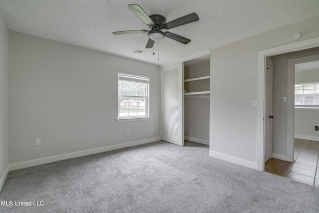 unfurnished bedroom featuring multiple windows, a textured ceiling, and light colored carpet