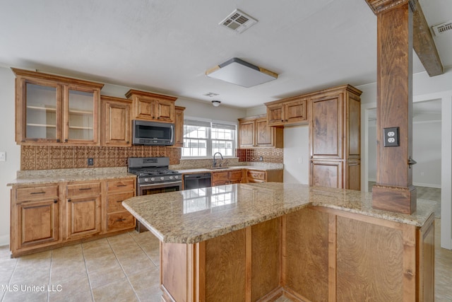 kitchen with appliances with stainless steel finishes, light stone counters, decorative backsplash, light tile patterned floors, and sink