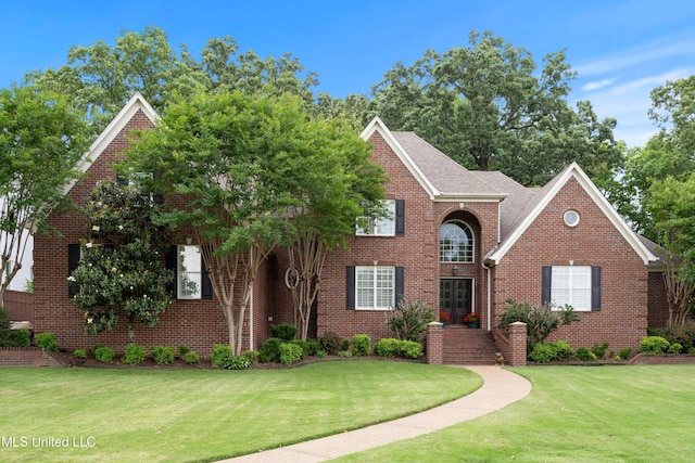 view of front of house featuring a front lawn, brick siding, and a shingled roof