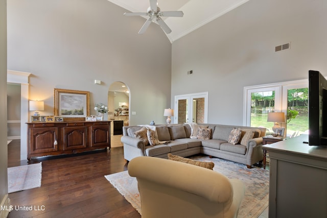 living area with high vaulted ceiling, arched walkways, crown molding, a ceiling fan, and dark wood-style floors