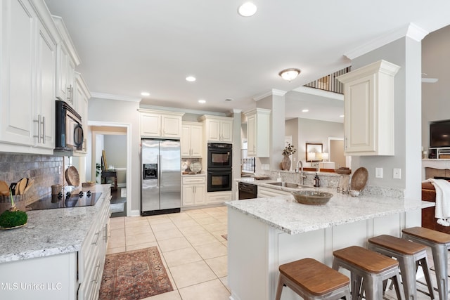 2038 Nottaway Dr, Southaven, MS 38672 - kitchen with black appliances, a sink, a peninsula, decorative backsplash, and a kitchen bar