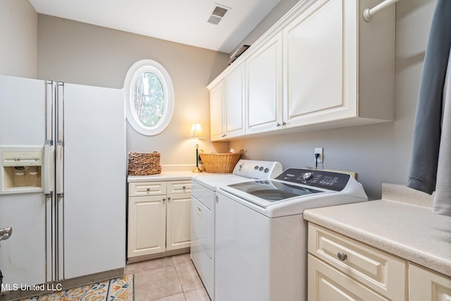 clothes washing area featuring cabinet space, separate washer and dryer, and light tile patterned floors