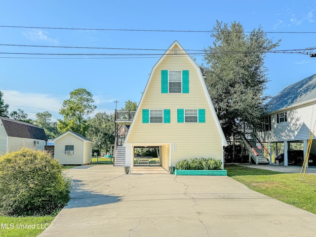 a-frame style home featuring a gambrel roof, driveway, and stairway