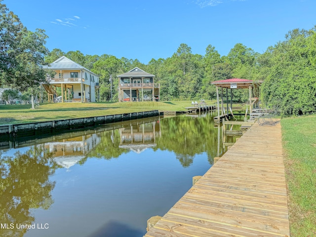 dock area with a balcony, a yard, and a water view