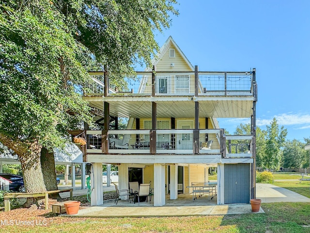 rear view of property with a patio area, a yard, and a balcony