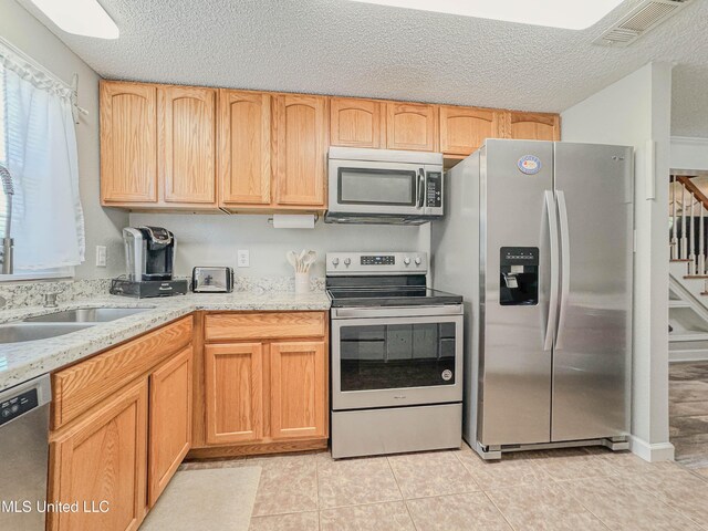 6085 Apache Dr, Kiln, MS 39556 - kitchen with visible vents, a textured ceiling, a sink, light tile patterned floors, and stainless steel appliances