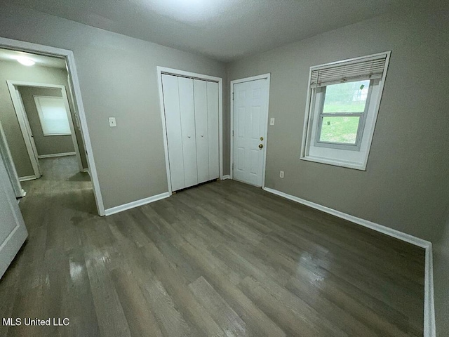 unfurnished bedroom with a closet, wood finished floors, and baseboards