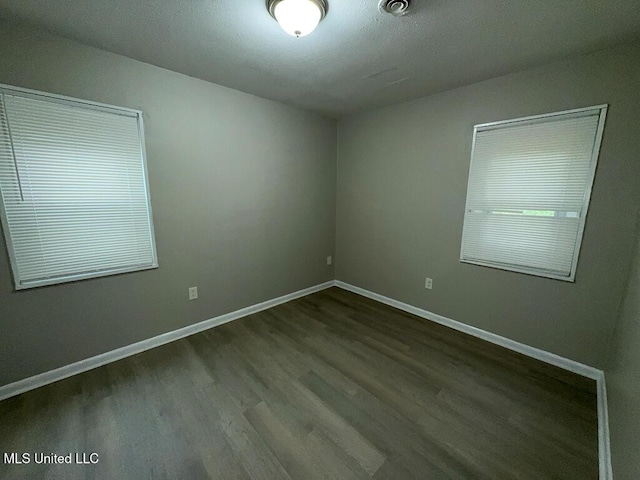 unfurnished room featuring dark wood-style floors and baseboards